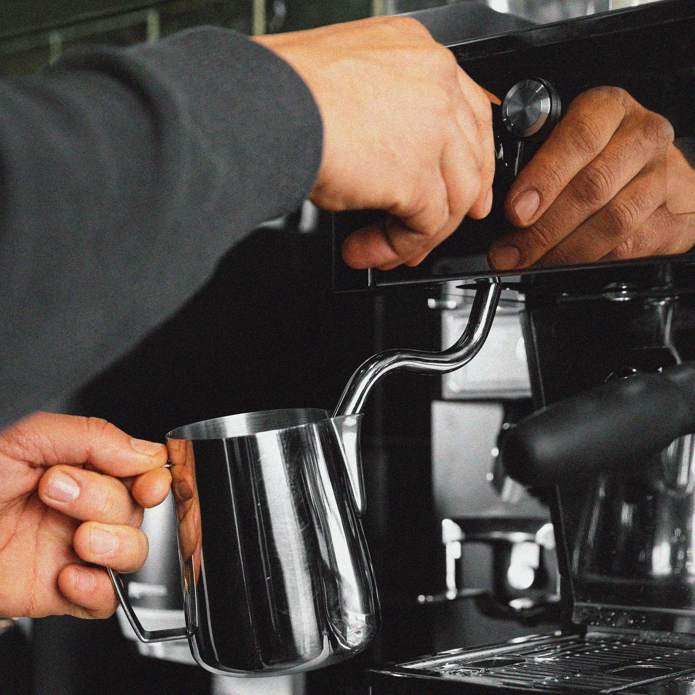 hands holding espresso machine milk frother