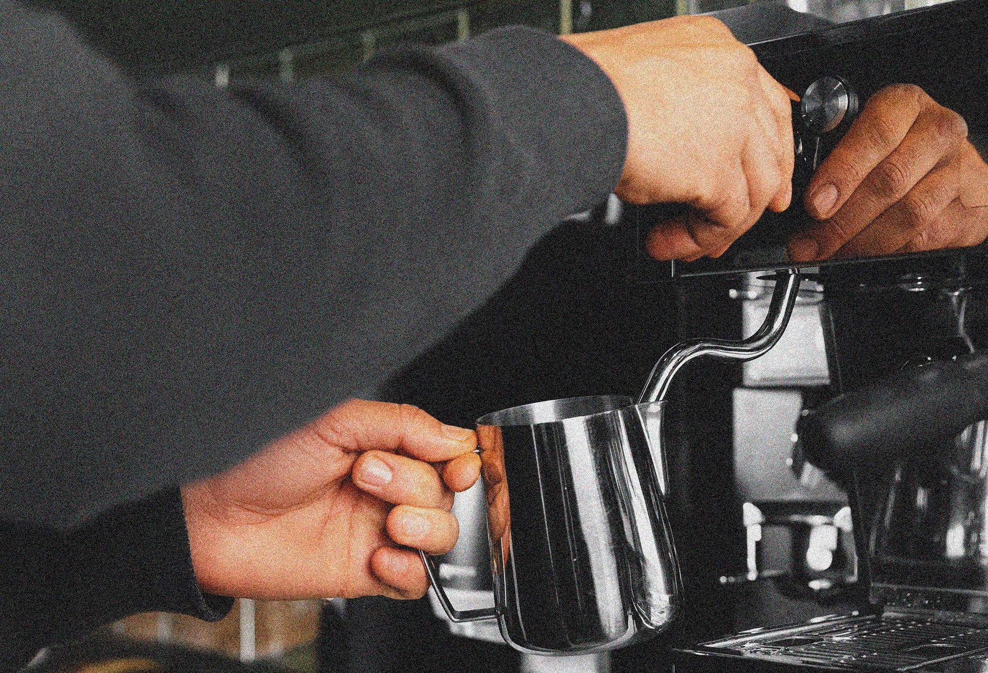 Person using a milk frother on an espresso machine - Browse restaurant equipment maintenance plans from Better Brands